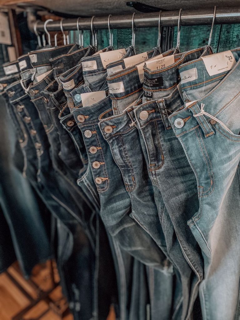 A photo of a vintage clothing rack filled with an assortment of denim jeans in various washes and styles, inviting the reader to embark on their own treasure hunt for the perfect pair.