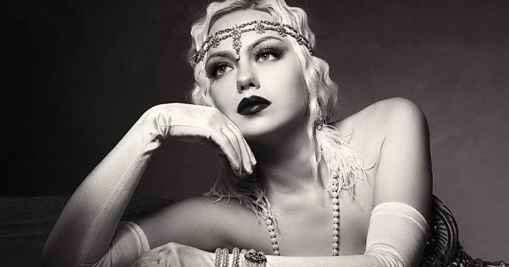 An image capturing the spirit of the 1920s flapper style, featuring a woman adorned in a glamorous beaded dress, with a feathered headpiece and statement accessories, radiating the vibrancy and rebelliousness of the Jazz Age.