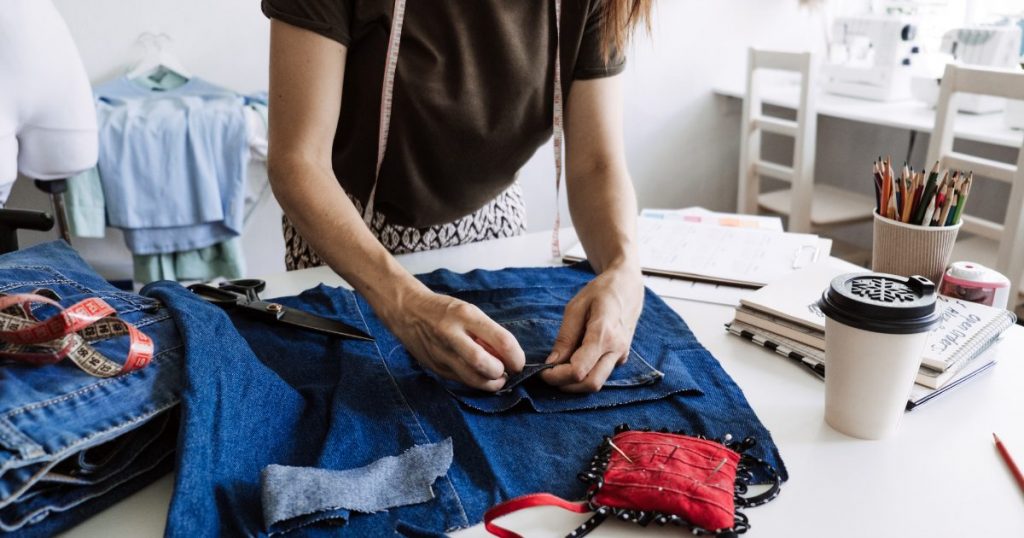 An image capturing a hands-on process of upcycling or repurposing vintage clothing, showcasing the transformation from old to new with a touch of creativity.